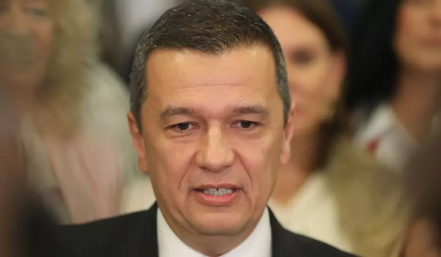 Sorin Grindeanu, ministrul Transporturilor, în prim plan, cu câțiva oameni în spate care apar blurați