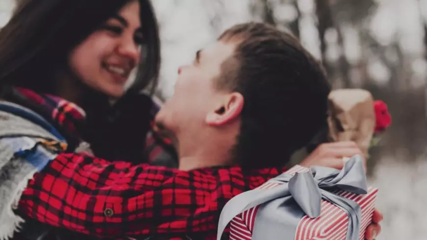 Iubitul dă o cutie cadou cu panglică de Un cuplu își face cadouri de Sfântul Valentin, Sursă: Profimedia