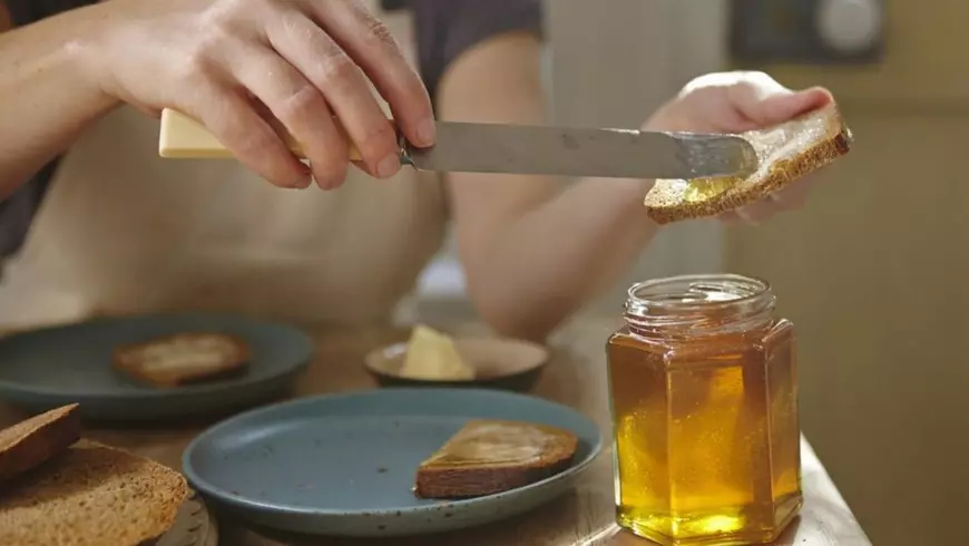 Femeie întinde miere pe pâine, Sursă foto: Profimedia