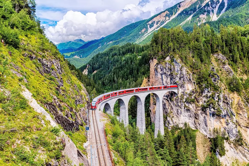 Munții Alpi – curiozități şi lucruri mai puţin cunoscute - Imagine cu trenul Glacier Express traversând un viaduct în Munţii Alpi.