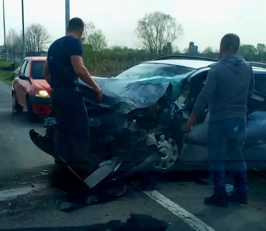 Poză cu pompierul aflat la locul accidentului. Chelariu Paul stă în fața unei mașini distruse, iar lângă el se află un bărbat. În fața vehiculului este o altă mașină roșie