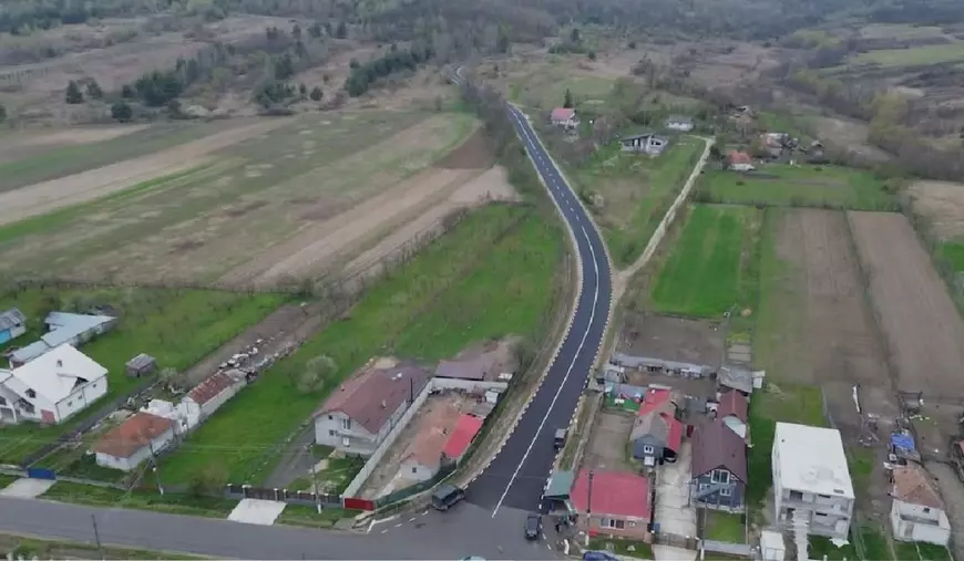 mai multe case și terenuri agricole despărțite de un drum proaspăt asfaltat