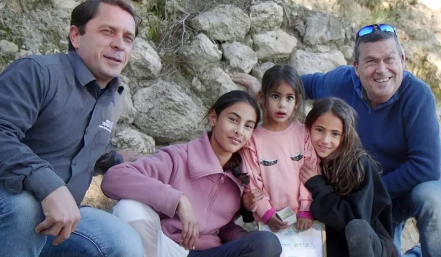 cinci persoane, doi bărbati, o femeie si 2 copii stau sa facă o fotografie cu niste pietre in spate