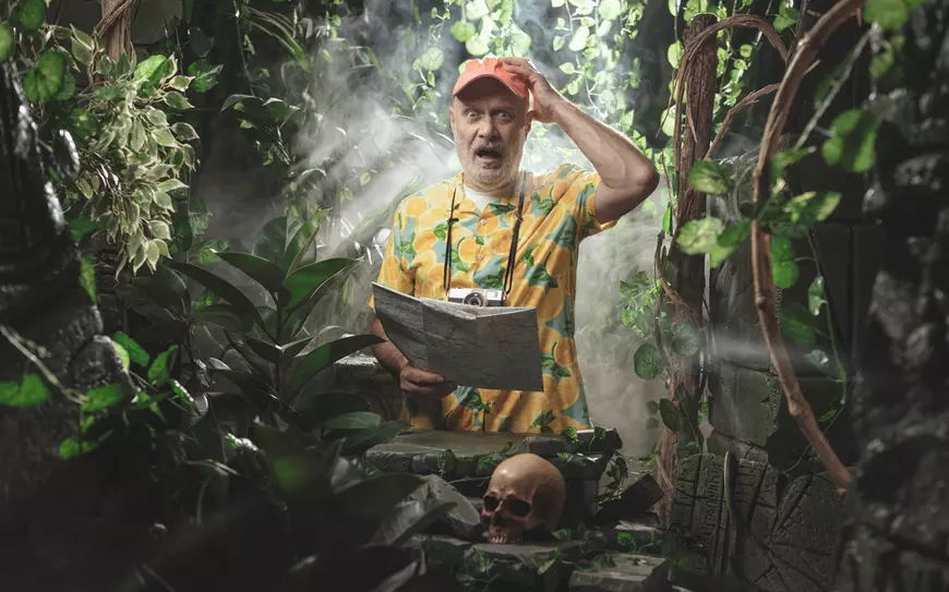 Turist cu o hartă în mână, speriat pentru că s-a pierdut în jungla tropicală