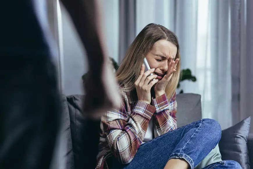 Femeie abuzata cere ajutor la telefon. Foto ilustrativ