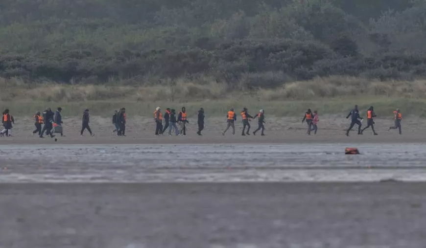 Imigranți ilegali transportați cu barca în Anglia, din Franța, merg pe jos în momentul în care au ajuns la țărm.