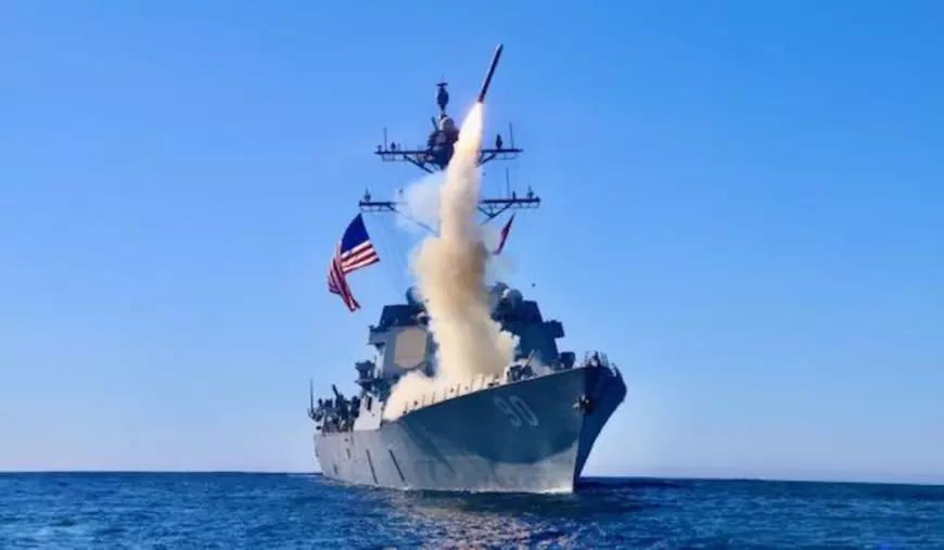 Navă pe apă, cu steagul SUA și o rachetă lansată.