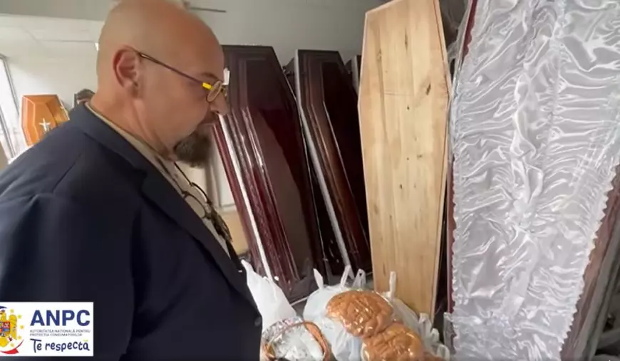 Cristian Popescu Piedone, președintele ANPC, cu tricou bej și sacou bluemarin, ochelari cu ramă galbenă și insigna la gât, stă cu mîinile la spate într-o încăpere în care sunt expuse mai multe sicrie
