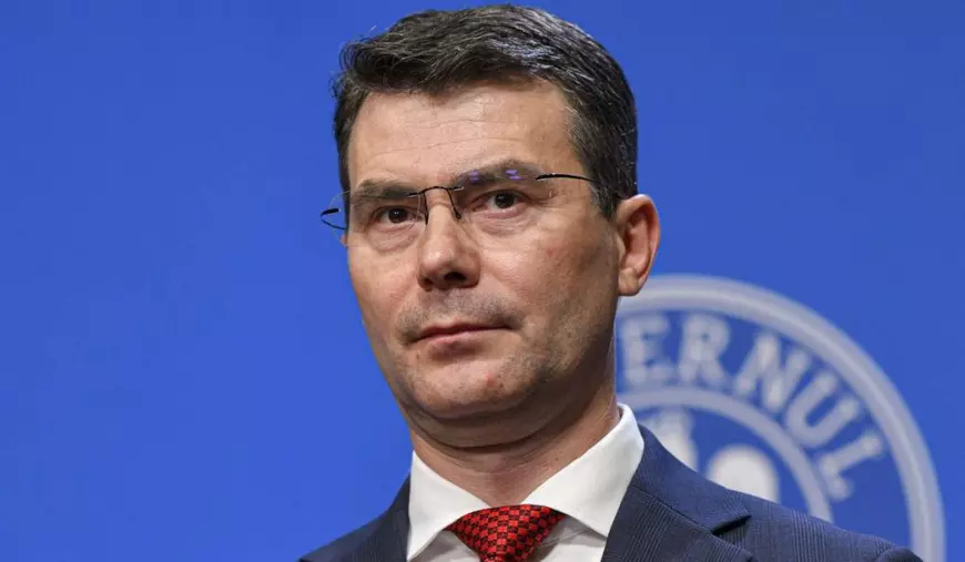 Horațiu Moldovan, șeful CNAS, în timpul unei conferințe de presă, poartă un costum albastru și o cravată roșie.