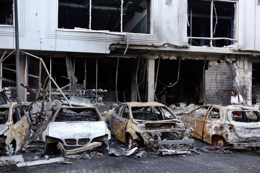 Imagine cu trei mașini incendiate după un atac al rușilor în Kiev. În spate se află o clădire distrusă. Foto din iulie 2025