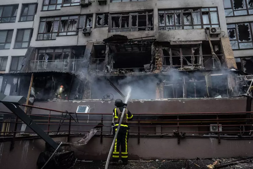 Imagine cu un pompier care se află la locul unui incendiu. În imagine se vede o clădire distrusă