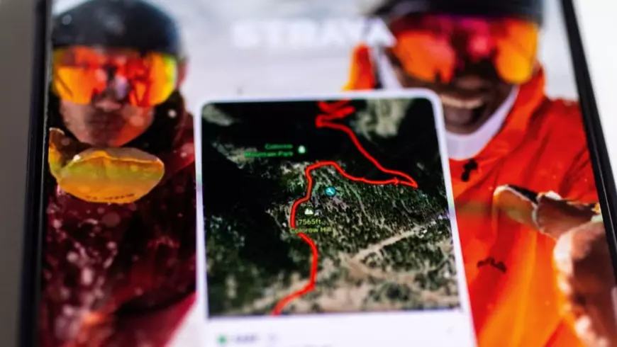 Imagine cu caracter ilustrativ cu aplicația Strava in prim plan , pe care se vede un traseu, si doua persoane intr-un fundal neclar,