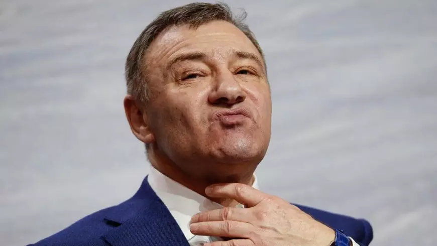 Oligarhul Arkadi Rotenberg, in sacou albastru si camasa alba, surprins in timp ce isi duce mana la gat
