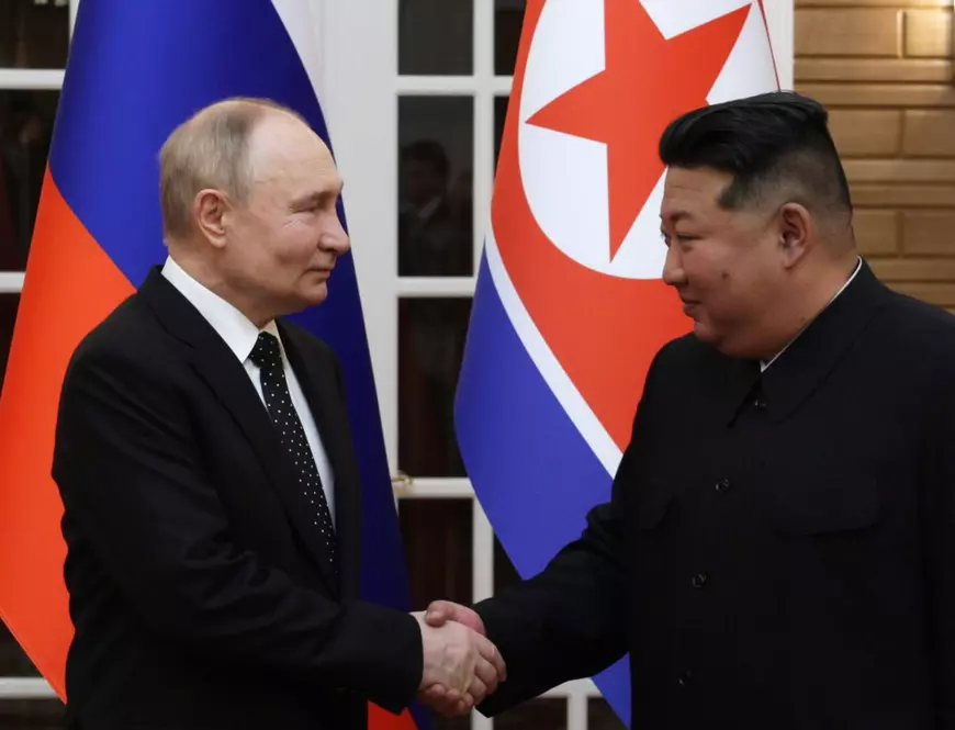 Vladimir Putin (stânga) și Kim Jong Un (dreapta) surprinși în timp ce-și strâng mâinile.