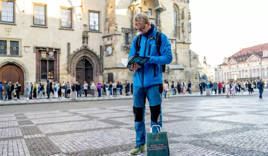 Un bărbat citește carte Dan Brown: Secretul tuturor secretelor, alți oameni stau la coadă în Praga pentru a umpăra cartea