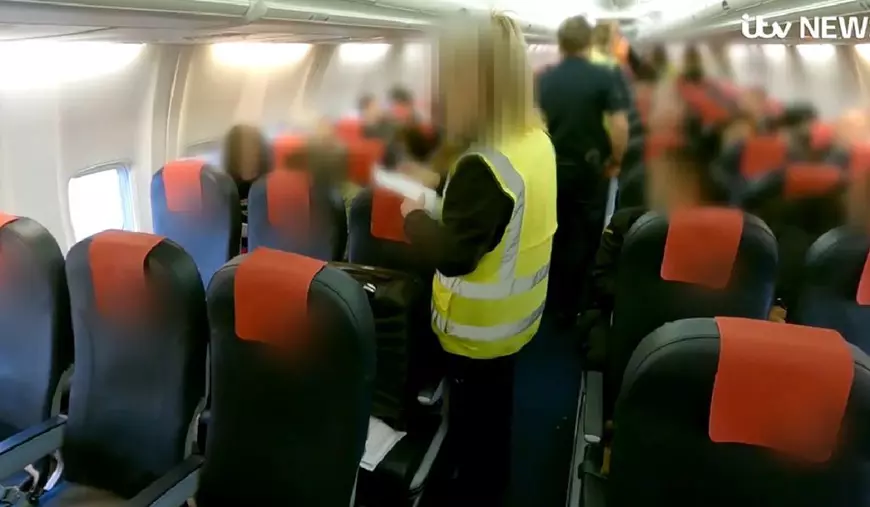 Imagini din avionul in care sunt deportati infractori români din Marea Britanie. Se văd scaunele și vestele galben fosforescent ale polițiștilor