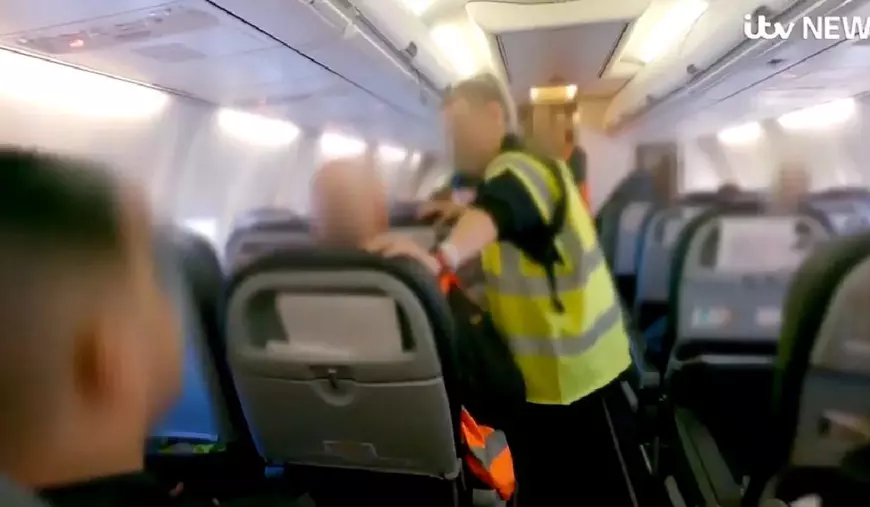 Imagini din avionul in care sunt deportati infractori români din Marea Britanie. Se văd scaunele și vestele galben fosforescent ale polițiștilor