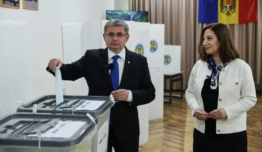 Ion Ceban, îmbrăcat într-un costum negru, cămașă albă și o cravată albastră cu picățele introduce un vot într-o urnă transparentă. În dreapta sa se află Tatiana Ceban, soția sa, îmbrăcată într-o rochie eagră, un cardigan alb cu nasturi aurii și o eșarfă bleumaren, ținând mâinile împreunate în fața abdomenului, uitându-se în stânga, către soțul său, Chișinău, 28 septembrie 2025