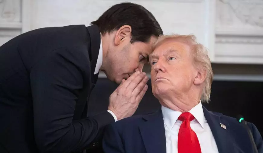 Marco Rubio, îmbrăcat în costum negru, îi șoptește ceva la ureche președintelui SUA Donald Trump
