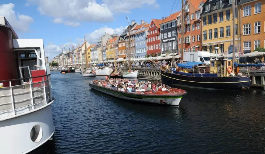 Copenhaga /Danemarca/06 august 2022/Turiști la cafenea, mâncând și bând și plimbându-se cu barca într-o zi însorită pe canalul Nyhvan din capitala daneză.