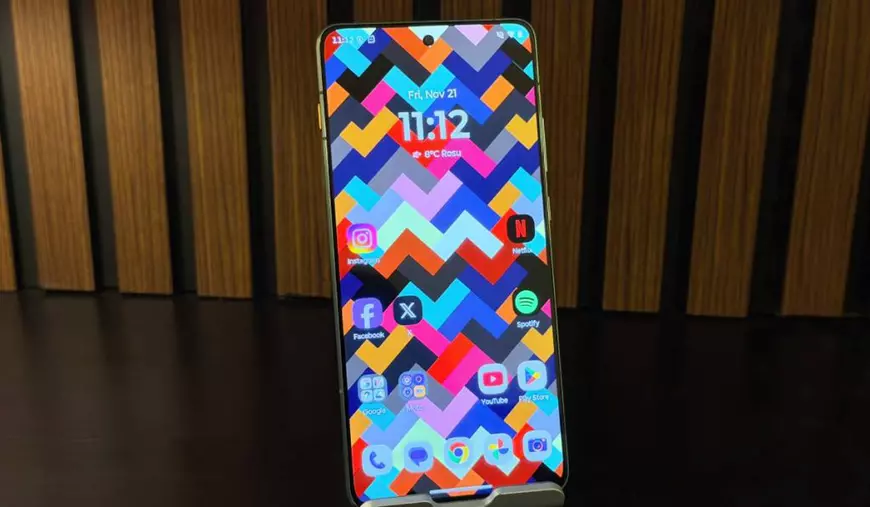 Poză cu ecranul lui Motorola Edge 70, pe un stativ, cu un fundal de lemn.