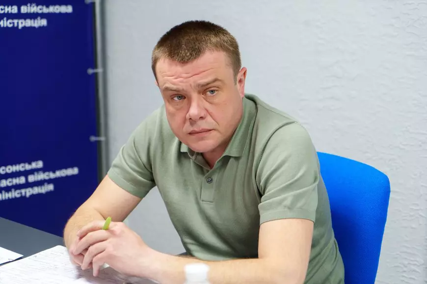 Un barbat in tricou verde sta la un birou