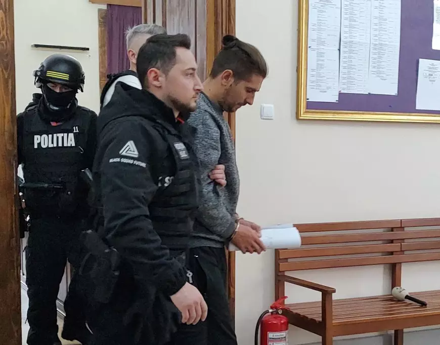 Cosmin Zuleam. imbracat in gri este scos din sala de judecata de doi ofiteri de politie imbracati in negru