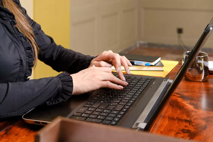 O femeie scrie la un computer