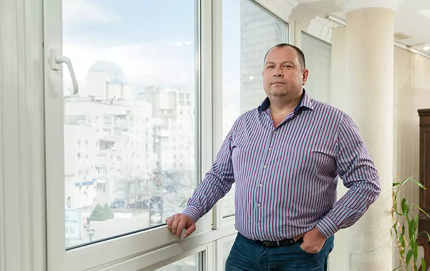 Un om de afaceri in camasa bleumarin cu dungi albe, lanha o fereastra