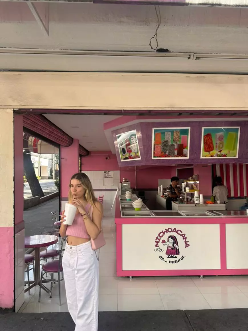 O tanara imbracată in alb bea suc dintr-un pahar cu paiul