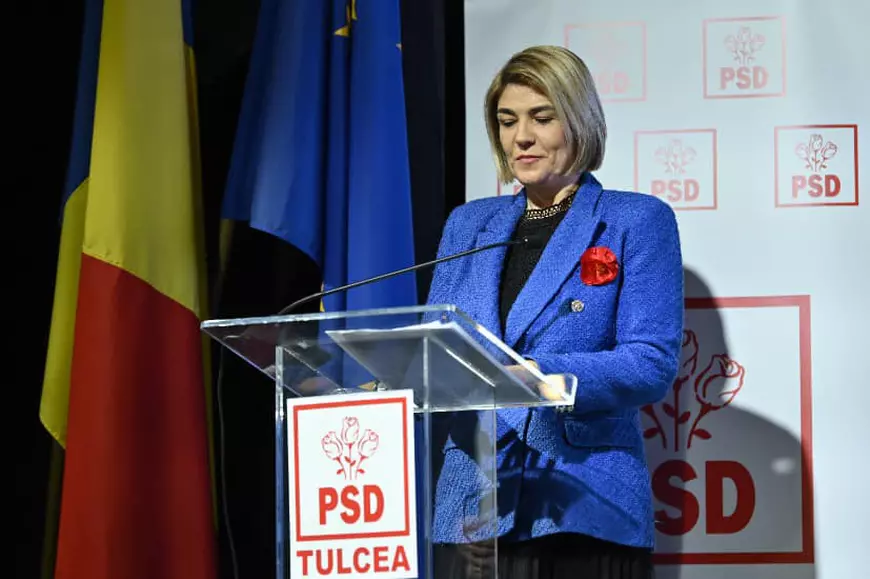 O doamna imbracata in costum albastru vorbeste la microfon