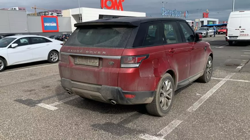 Range Rover Sport, de culoare roșie, fotografiat din spate, în parcarea centrului comercial Tom Carrefour din Constanța