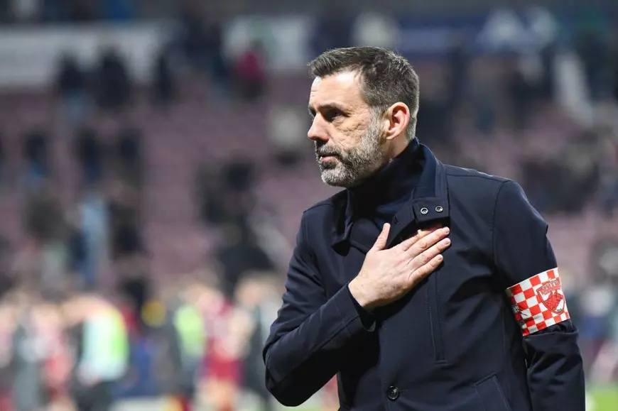 Zeljko Kopic, antrenor Dinamo Bucuresti, imbracat intr-o tinuta neagra, pune mana la inima in fata fanilor