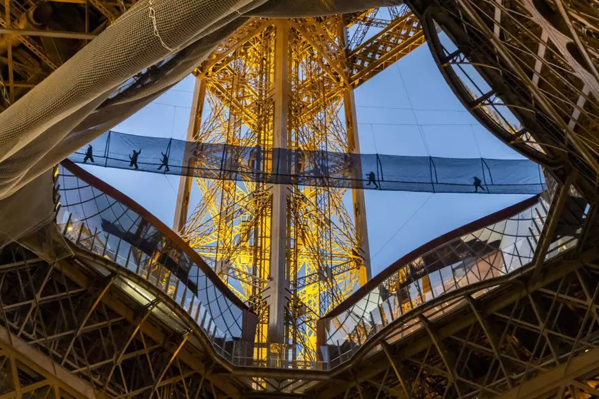 Paris, Franța, 18 martie 2026 – Oamenii traversează podul suspendat „Vertigo of the Tower” de la Turnul Eiffel. 