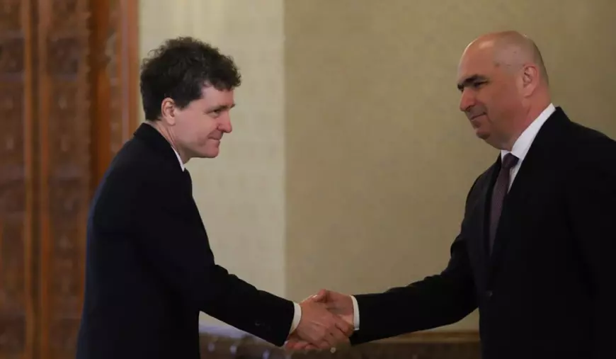 Nicușor Dan și Ilie Bolojan, îmbrăcați în costume închise la culoare își strâng mâinile înainte de discuțiile privind criza politică.