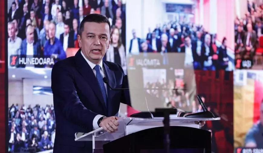 Sorin Grindeanu, îmbrăcat în costum negru, cămașă albă și cravată albastră, la pupitru cu microfoane, iar pe fundal ecrane pe care se văd blurați membrii PSD