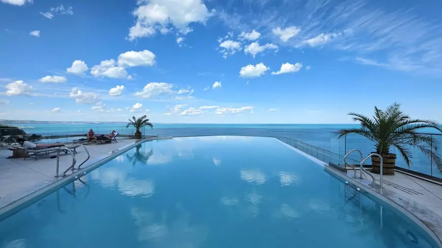 infinity pool, apa si cerul albastru creeaza o impresie puternica. in plan indepartat se vede marea turcoaz