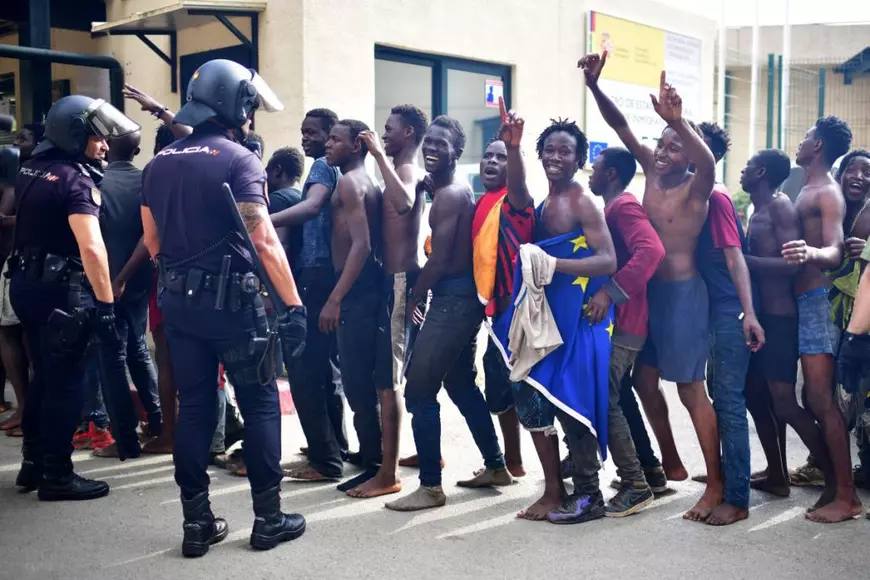 Migranți așteaptă la coadă în fața Centrului de Reședință Temporară pentru Imigranți (CETI), după ce au reușit să treacă frontiera din Maroc în enclava spaniolă Ceuta, la 22 august 2018, în Ceuta, Spania