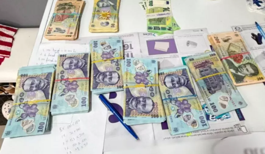 Teancuri de bani în bancnote de 50, 100, 200 de lei și 100 de euro, întinși pe o masă de culoare albă, cu un pix lângă și o bucată de hârtie