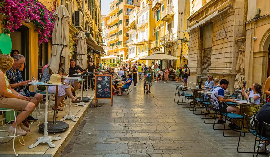 O stradă din Corfu cu rerstaurante și mulți clienți la mese.